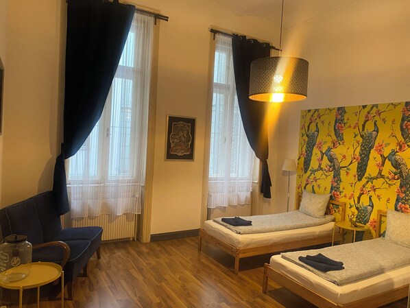 Une chambre avec deux lits simples, un canapé, une petite table et une lampe.