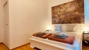 A bedroom with a bed, a painting on the wall, and a wooden floor.