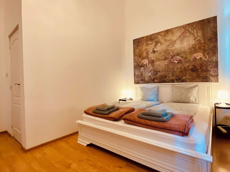 Une chambre à coucher avec un lit, un tableau accroché au mur et un plancher en bois.