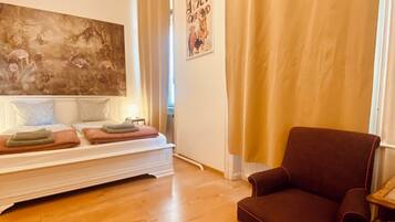 Un salon avec un canapé, un fauteuil, un grand tableau et une affiche accrochée au mur.