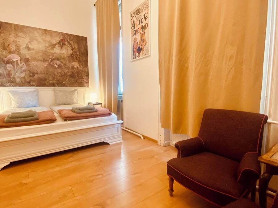 Un salon avec un canapé, un fauteuil, un grand tableau et une affiche accrochée au mur.
