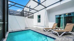 Une piscine extérieure moderne, avec une eau d’un bleu cristallin, entourée d’un bâtiment blanc doté de grandes fenêtres et d’une structure de plafond en verre.