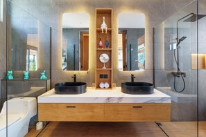 A modern bathroom with two sinks, a mirror, and a shower.