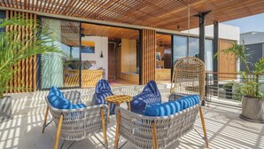 A modern outdoor seating area with wicker furniture and blue cushions, a wooden ceiling, and potted plants. - Sophisticated 3-Bedroom Designer Pool Villa in Central Seminyak (Badung)