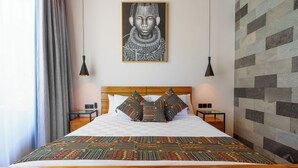 A neatly made bed with a patterned bedspread, a wooden headboard, and two bedside tables with lamps. - Sophisticated 3-Bedroom Designer Pool Villa in Central Seminyak (Badung)