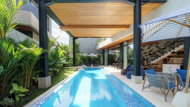 A modern pool area with a clear blue pool, surrounded by lush greenery and outdoor seating. - Sophisticated 3-Bedroom Designer Pool Villa in Central Seminyak (Badung)