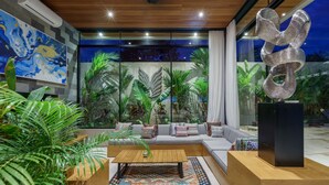 A modern living room with a wooden coffee table, a sofa, and a large abstract sculpture. - Sophisticated 3-Bedroom Designer Pool Villa in Central Seminyak (Badung)