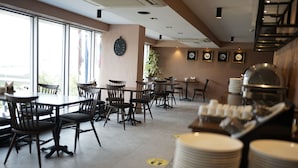 A restaurant with multiple tables and chairs, a clock on the wall, and a buffet area with stacked plates. - WEEN OTEL (Trabzon)