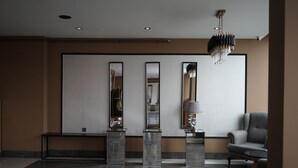 A modern lobby with a marble floor, a grey armchair, and a chandelier. - WEEN OTEL (Trabzon)