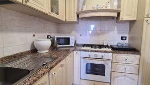 Een keuken met witte kastjes, een granieten aanrecht, een magnetron, een fornuis en een spoelbak.