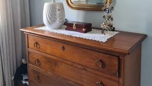 Een houten dressoir met drie lades, een witte vaas, een klein rode doosje en een decoratief metalen object.