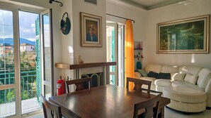 Een eethoek met een houten tafel en stoelen, een bank en een schilderij aan de muur.