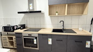 A modern kitchen with a double sink, built-in oven, and a microwave. - City apartment - central with beautiful terrace (Herne)