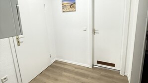 A room with a wooden floor, white walls, a door with a vent, and a small picture on the wall. - City apartment - central with beautiful terrace (Herne)