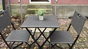 A patio with a table and chairs, a potted plant, and a building entrance. - City apartment - central with beautiful terrace (Herne)