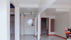 A spacious hallway with white tiled floors and red-framed doors leading to rooms.