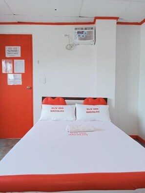 Une chambre d’hôtel avec un lit, une porte rouge et un climatiseur fixé au mur.