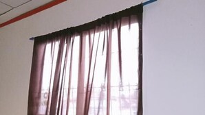 A window with a brown curtain, white walls, and a red trim.