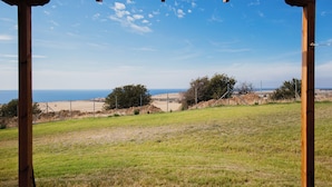 A view from a wooden structure with a clear sky and a beach in the distance. - Pezoulia Cottages (Samothrace)