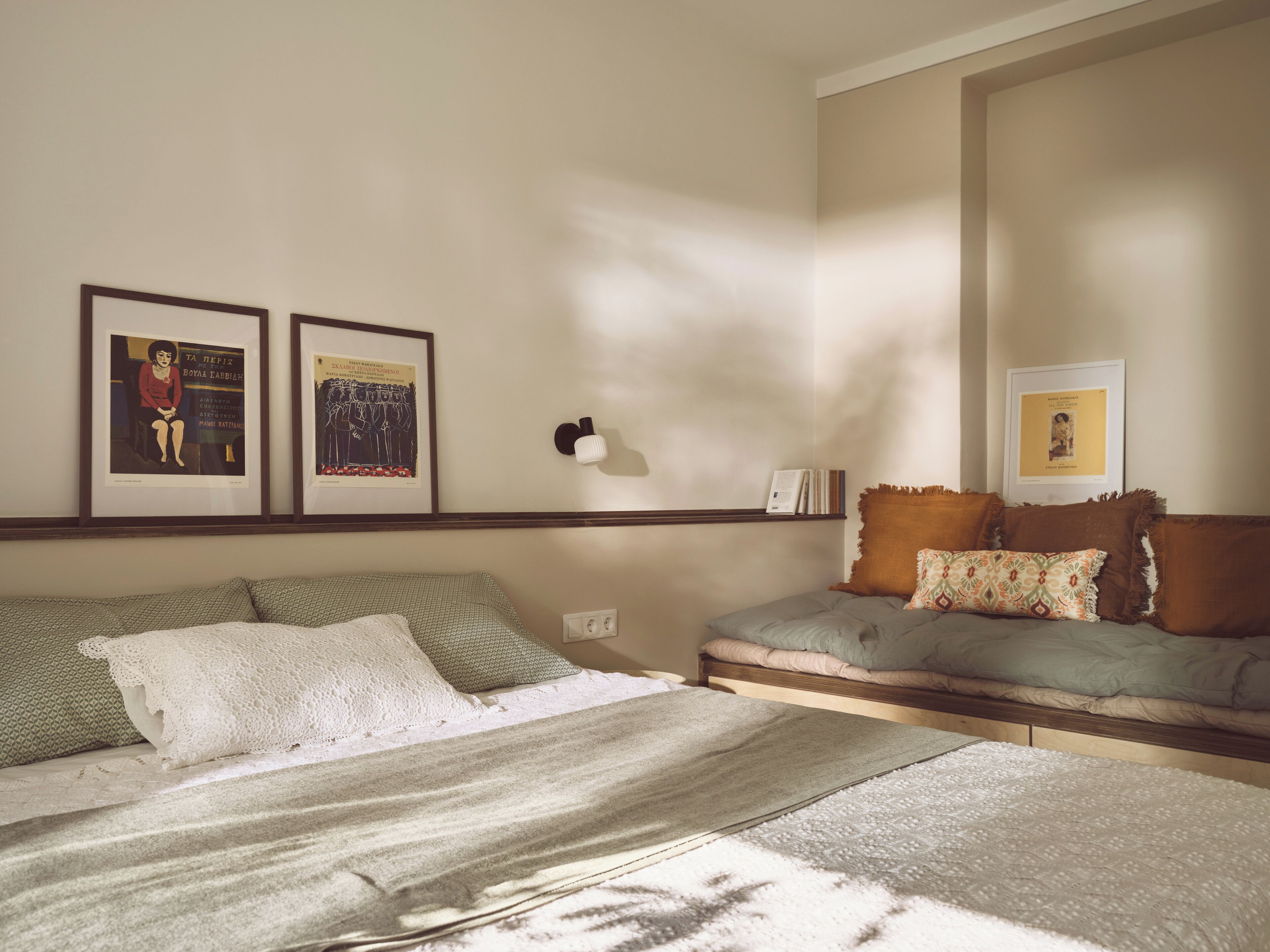 A bedroom with a bed, a sofa, and two framed pictures on the wall.