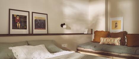 A bedroom with a bed, a sofa, and two framed pictures on the wall.