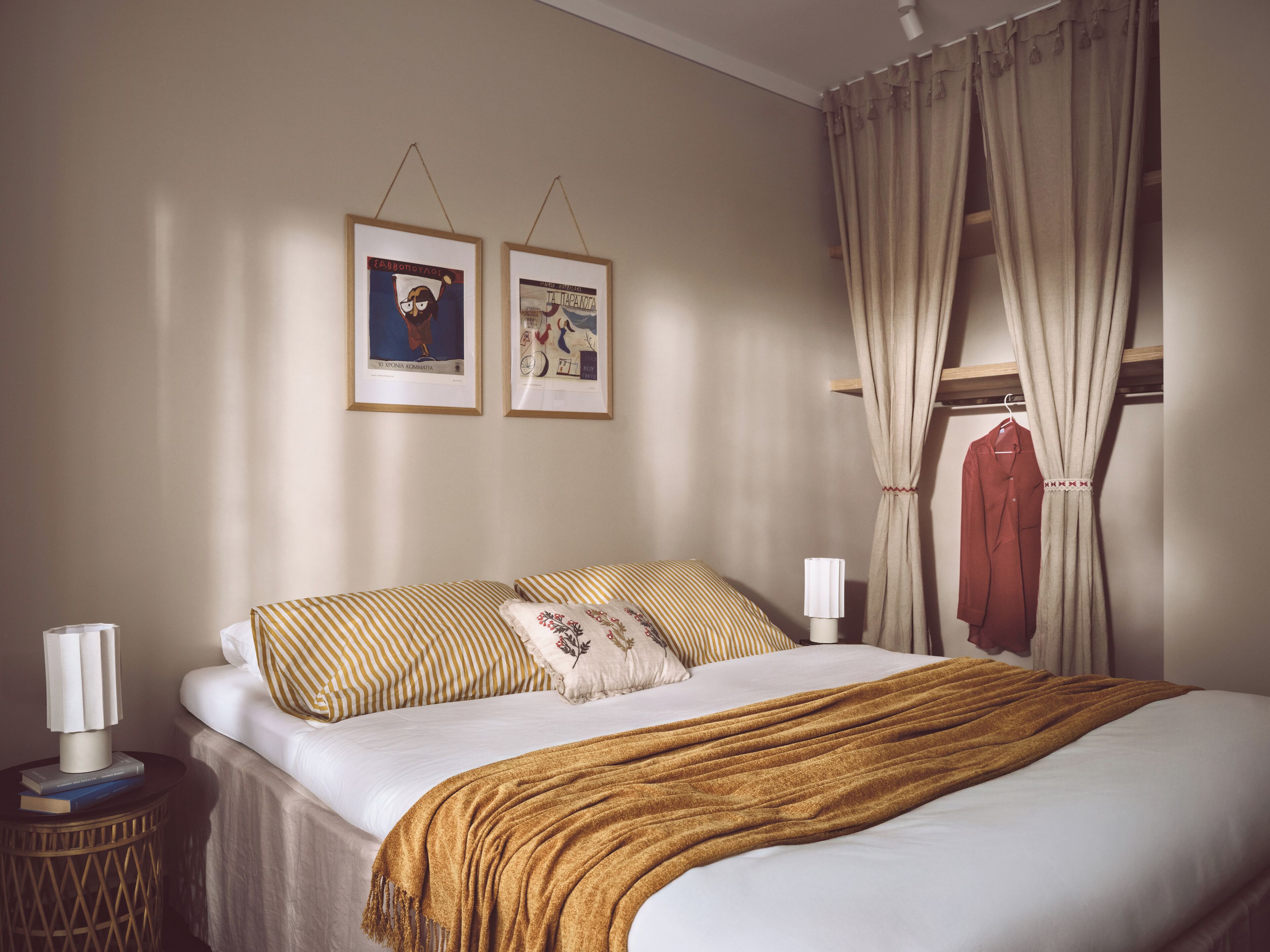 A neatly made bed with a striped pillow, a brown throw blanket, and a framed picture on the wall.