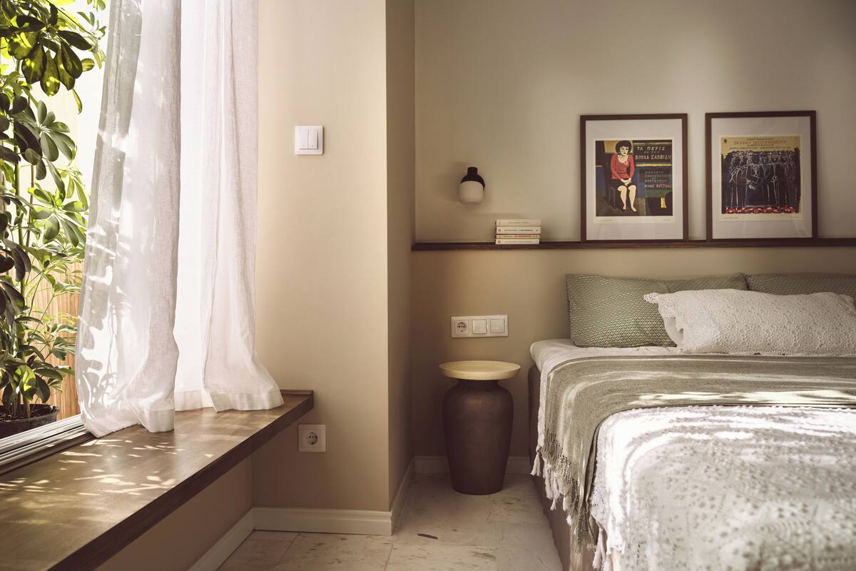 A bedroom with a bed, bedside table, lamp, and two framed pictures on the wall.
