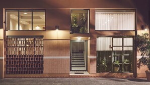 A modern building with a wooden facade, large windows, and a visible staircase leading to an upper level. - Melpomeni House (Athens)