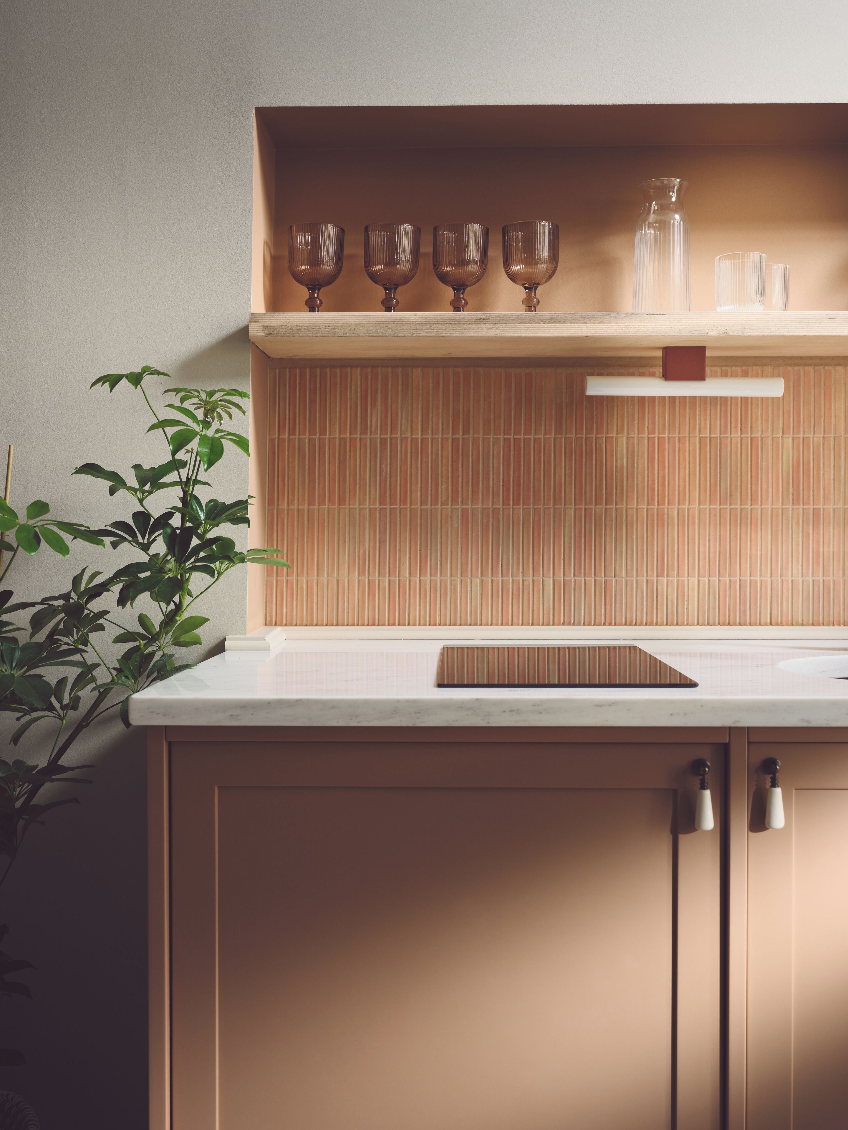 A kitchen with a wooden countertop, a bamboo backsplash, and a potted plant.