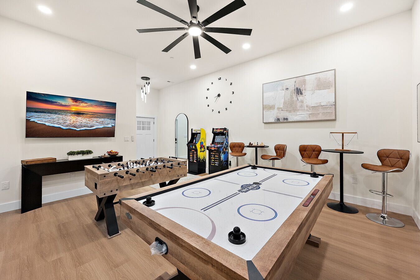Een kamer met een tafelvoetbaltafel, een pooltafel en een bar met krukken.