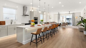 A modern kitchen with a central island, bar stools, and pendant lighting.