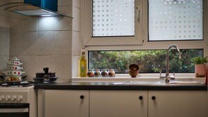 Una cucina con finestra, un fornello e pensili.