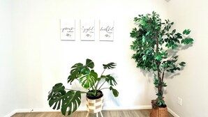 A corner room with wooden flooring, three wall-mounted signs with inspirational quotes, and two potted plants. - Modern 4BR 3BA Home, Minutes to NASA, Downtown & Galveston (Friendswood)
