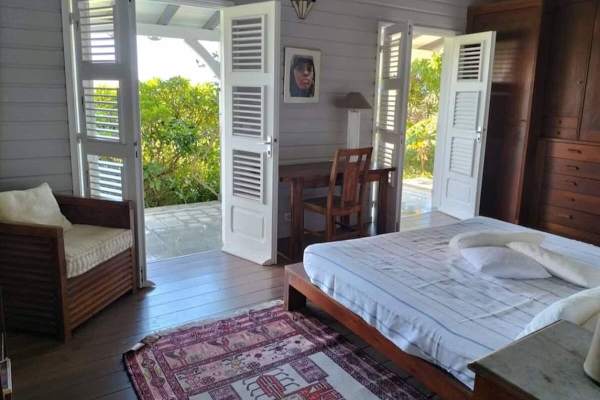 Un dormitorio con cama, una silla, un escritorio y un armario.