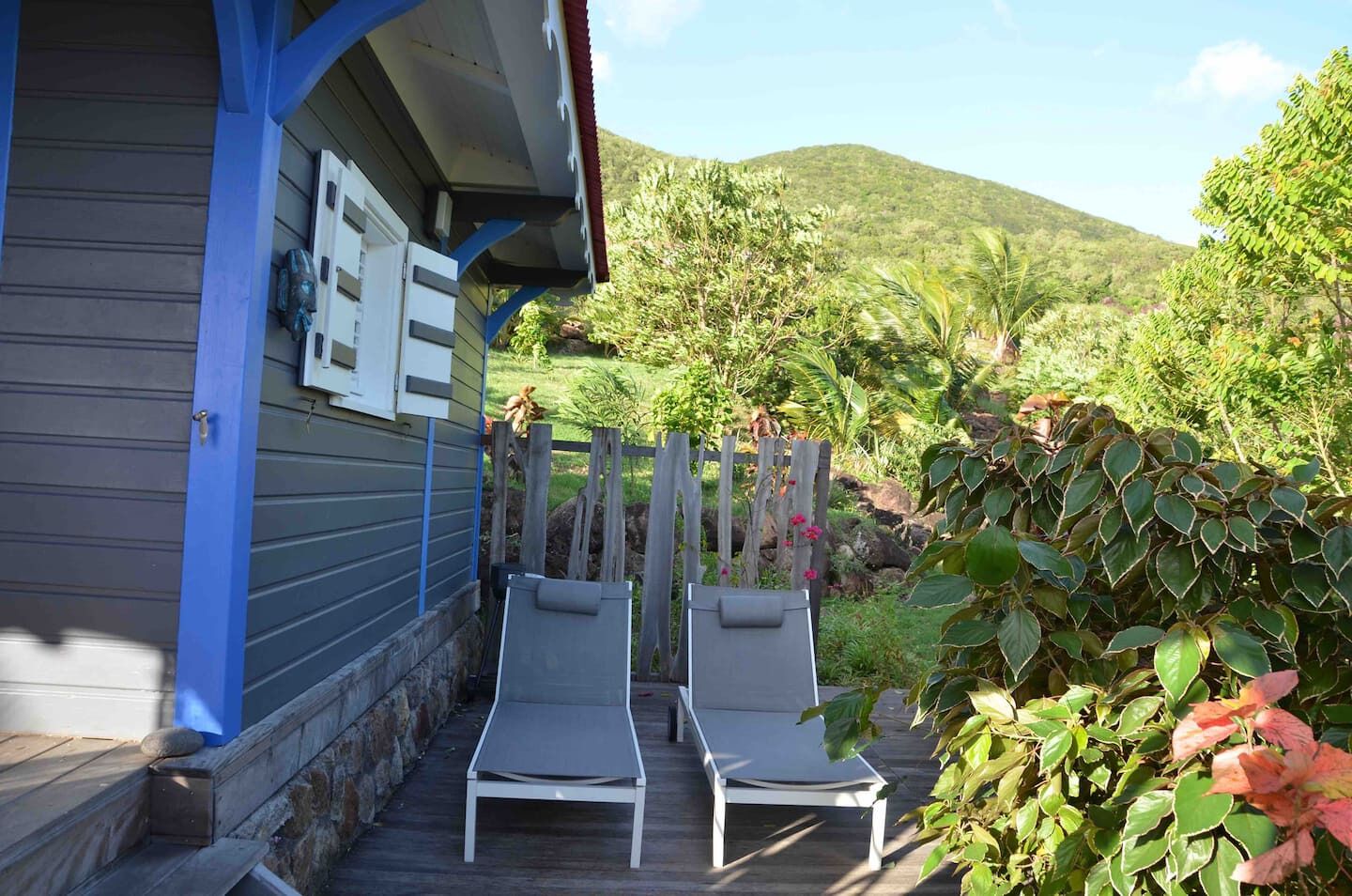 Un patio in legno con due poltrone da relax e una casa con decorazioni azzurre.