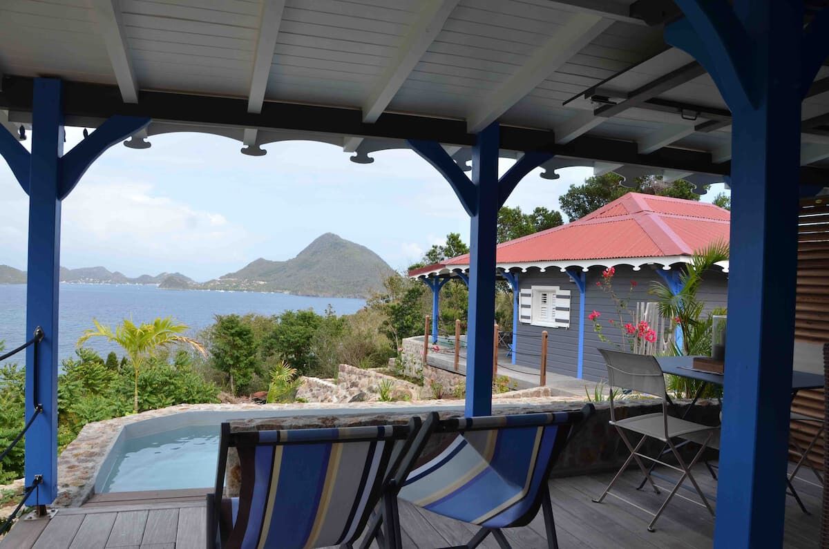 Un espace extérieur abrité comprenant une piscine, des chaises et une vue sur la mer et les montagnes.