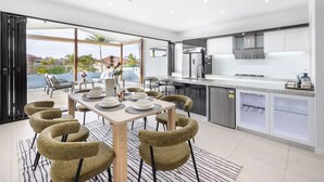 Een moderne keuken met een eetgedeelte, met een groot eiland, inbouwapparatuur en uitzicht op de omgeving.