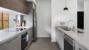 A modern kitchen with stainless steel appliances, a white countertop, and a pendant light. - Brand New! Convenient Family Home w/ Workspace (Park Ridge)