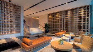 Eine moderne Lobby mit Schachbrettmuster-Boden, einer Treppe und einer Sitzecke mit Sofa und Sesseln.