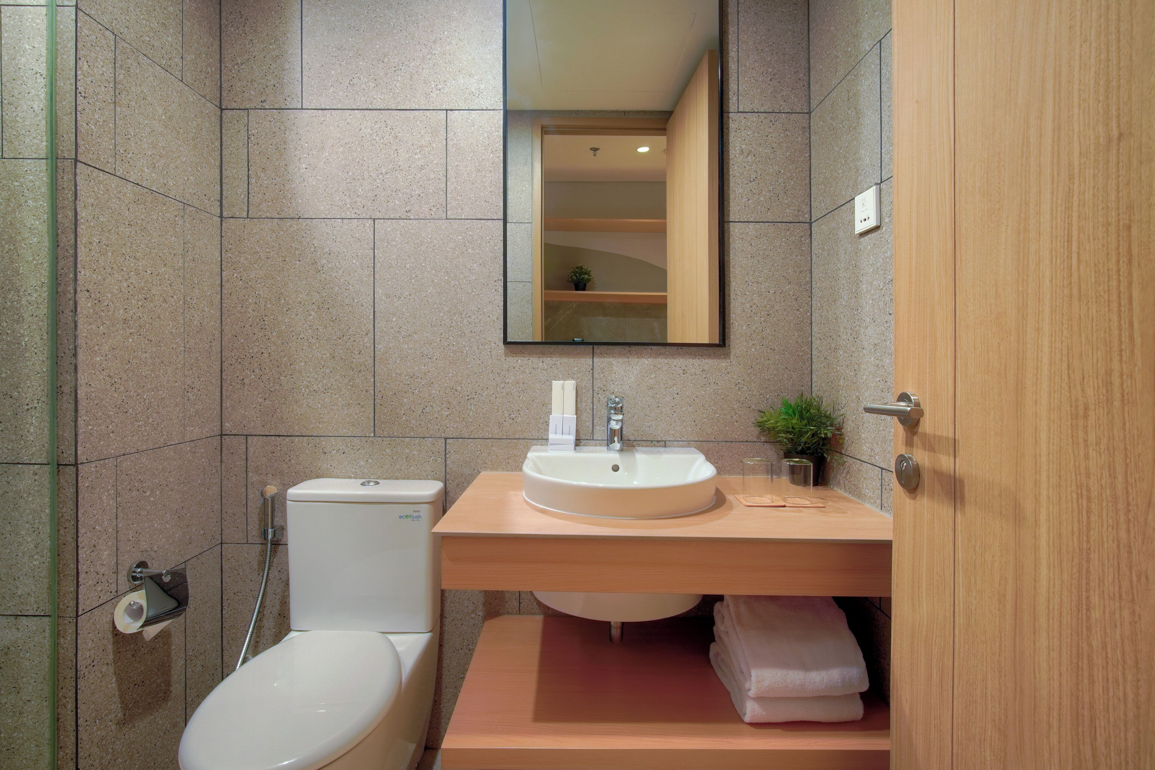 Un baño moderno con inodoro, lavamanos y espejo.