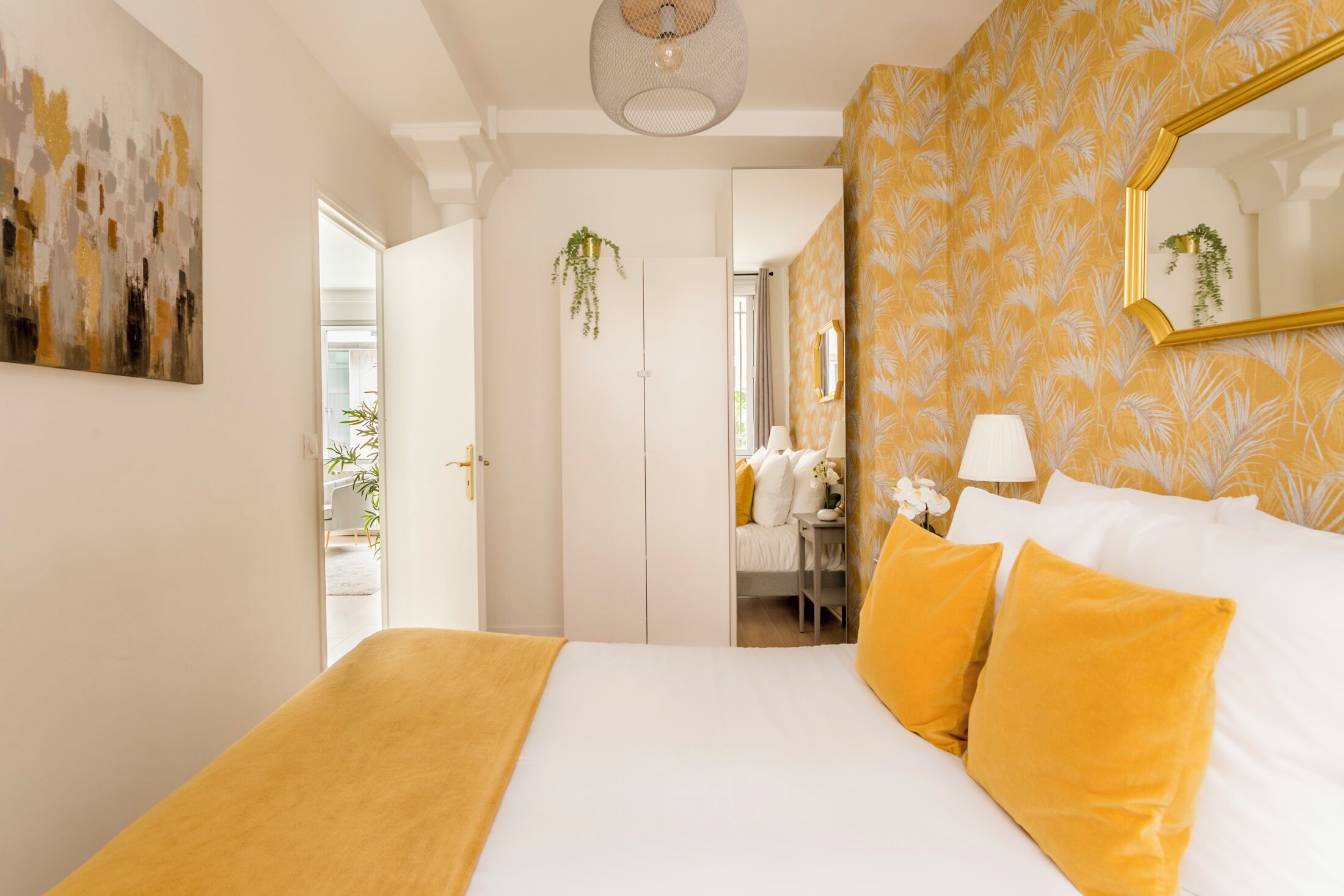 Une chambre à coucher avec un lit, une table de chevet, une lampe et un miroir.