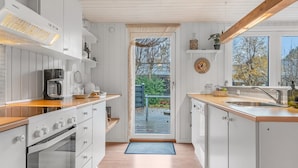 A modern kitchen with white cabinetry, a built-in oven, a coffee maker, and a large window offering a view of the outdoors.