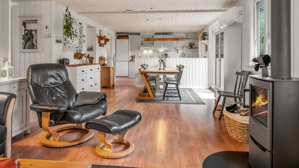 A modern kitchen with white cabinetry, a central island, and a wood-burning stove.