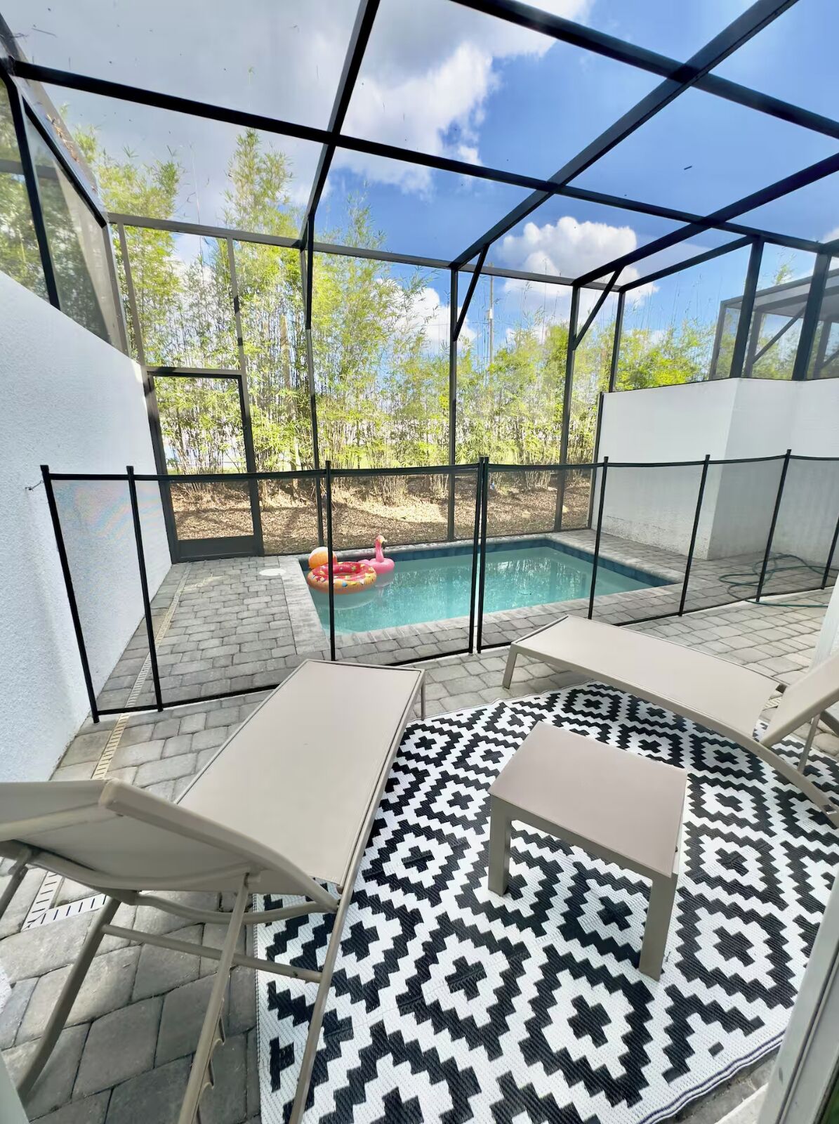 A covered outdoor area with a pool, lounge chairs, and a patterned floor.