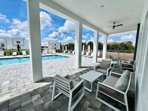 A covered outdoor area with a pool, lounge chairs, and a ceiling fan. - The Honeymoon Retreat by Disney/Universal/seaworld (Davenport)