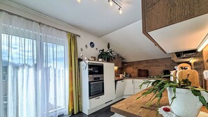 Una cocina moderna con armarios blancos, encimera de madera y horno empotrado.
