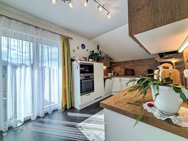 Une cuisine moderne avec des armoires blanches, un plan de travail en bois et un four encastré.