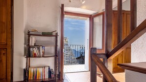 Una escalera de madera conduce a un balcón con vistas a un edificio de piedra y montañas.