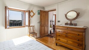 Un dormitorio con tocador de madera, espejo, silla y cama.