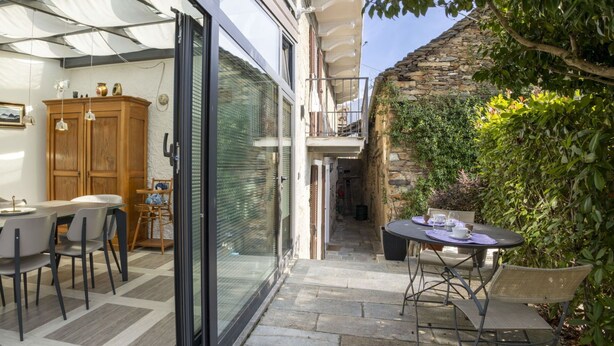 Un patio con mesa y sillas, un armario de madera y un cristal que da a un espacio exterior cubierto.